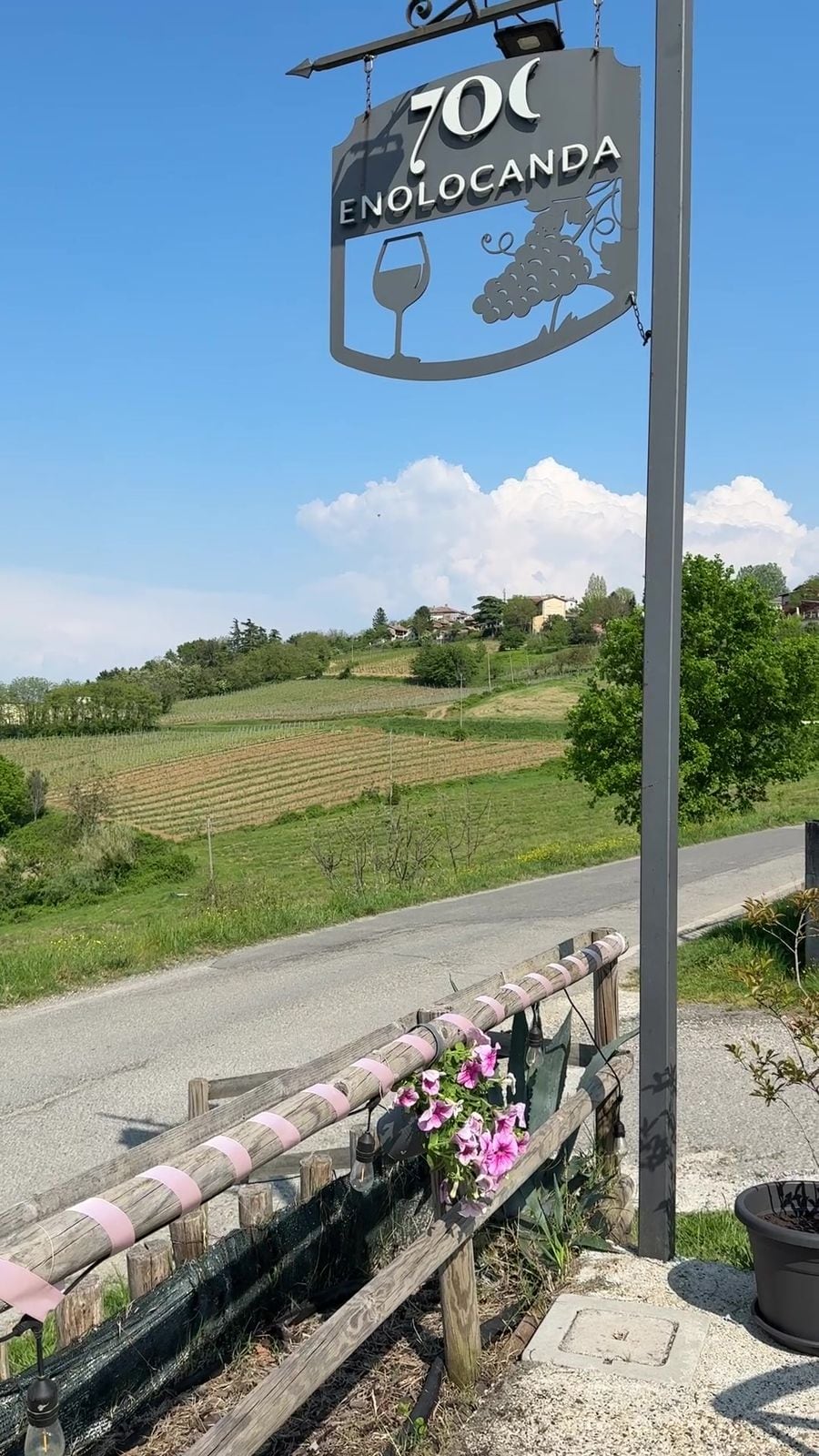 L’insegna di 700 Enolocanda accanto alla strada e ai vigneti